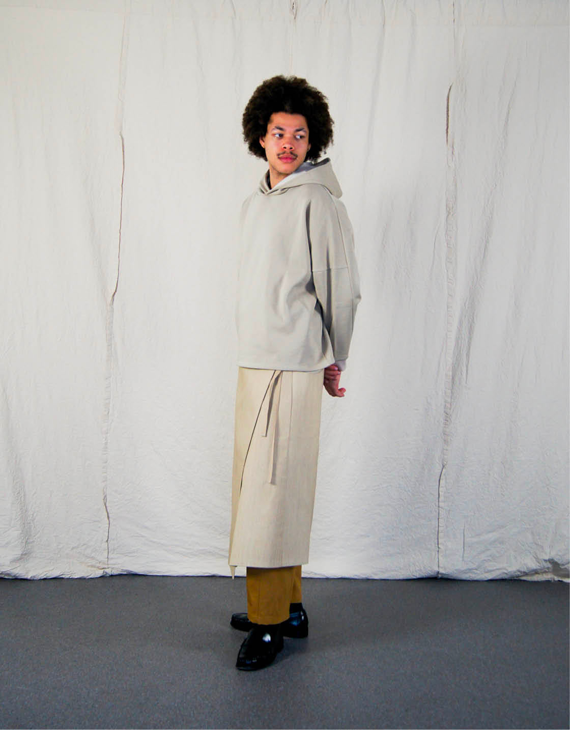 Hoodie - Chapitre 1, coupe droite, oversized, emmanchures basses, découpes asymétriques, capuche doublée, dans un camaïeu de molletons grattés beiges.  Hoodie - Chapter 1, straight cut, oversized, low armholes, asymmetrical lines, lined hood, in a cameo of beige brushed fleece.