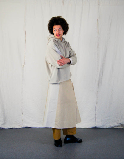 Hoodie - Chapitre 1, coupe droite, oversized, emmanchures basses, découpes asymétriques, capuche doublée, dans un camaïeu de molletons grattés beiges.  Hoodie - Chapter 1, straight cut, oversized, low armholes, asymmetrical lines, lined hood, in a cameo of beige brushed fleece.