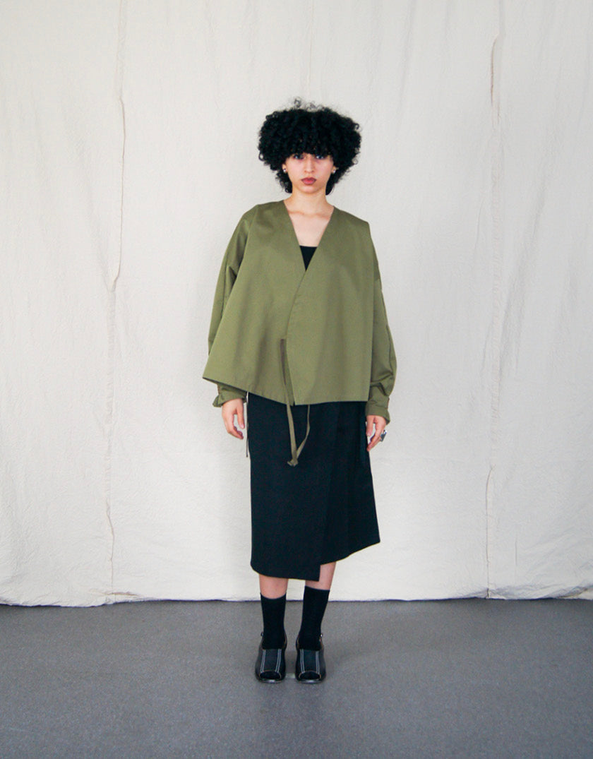 Jupe Chapitre 1, portefeuille, deux poches latérales, taille ajustable avec cordons passant dans deux passants au dos, dans un camaïeu de sergé de coton noir.  Chapter 1 skirt, wrapped, two side pockets, adjustable waist with drawstrings passing through two loops at the back, in a cameo of black cotton canvas.