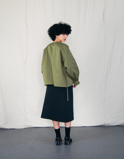 Jupe Chapitre 1, portefeuille, deux poches latérales, taille ajustable avec cordons passant dans deux passants au dos, dans un camaïeu de sergé de coton noir.  Chapter 1 skirt, wrapped, two side pockets, adjustable waist with drawstrings passing through two loops at the back, in a cameo of black cotton canvas.