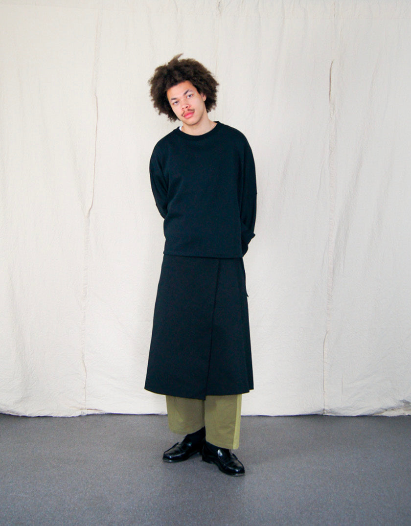 Jupe Chapitre 1, portefeuille, deux poches latérales, taille ajustable avec cordons passant dans deux passants au dos, dans un camaïeu de sergé de coton noir.  Chapter 1 skirt, wrapped, two side pockets, adjustable waist with drawstrings passing through two loops at the back, in a cameo of black cotton canvas.