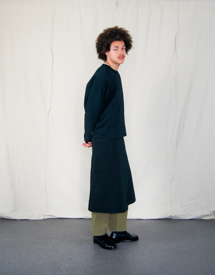 Jupe Chapitre 1, portefeuille, deux poches latérales, taille ajustable avec cordons passant dans deux passants au dos, dans un camaïeu de sergé de coton noir.  Chapter 1 skirt, wrapped, two side pockets, adjustable waist with drawstrings passing through two loops at the back, in a cameo of black cotton canvas.