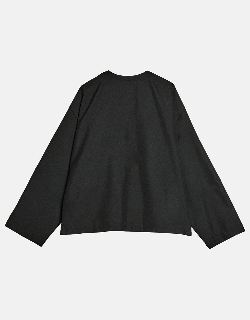 Minimalist black garment with wide sleeves and a loose fit, designed for comfortable movement and understated elegance in a contemporary unisex style.