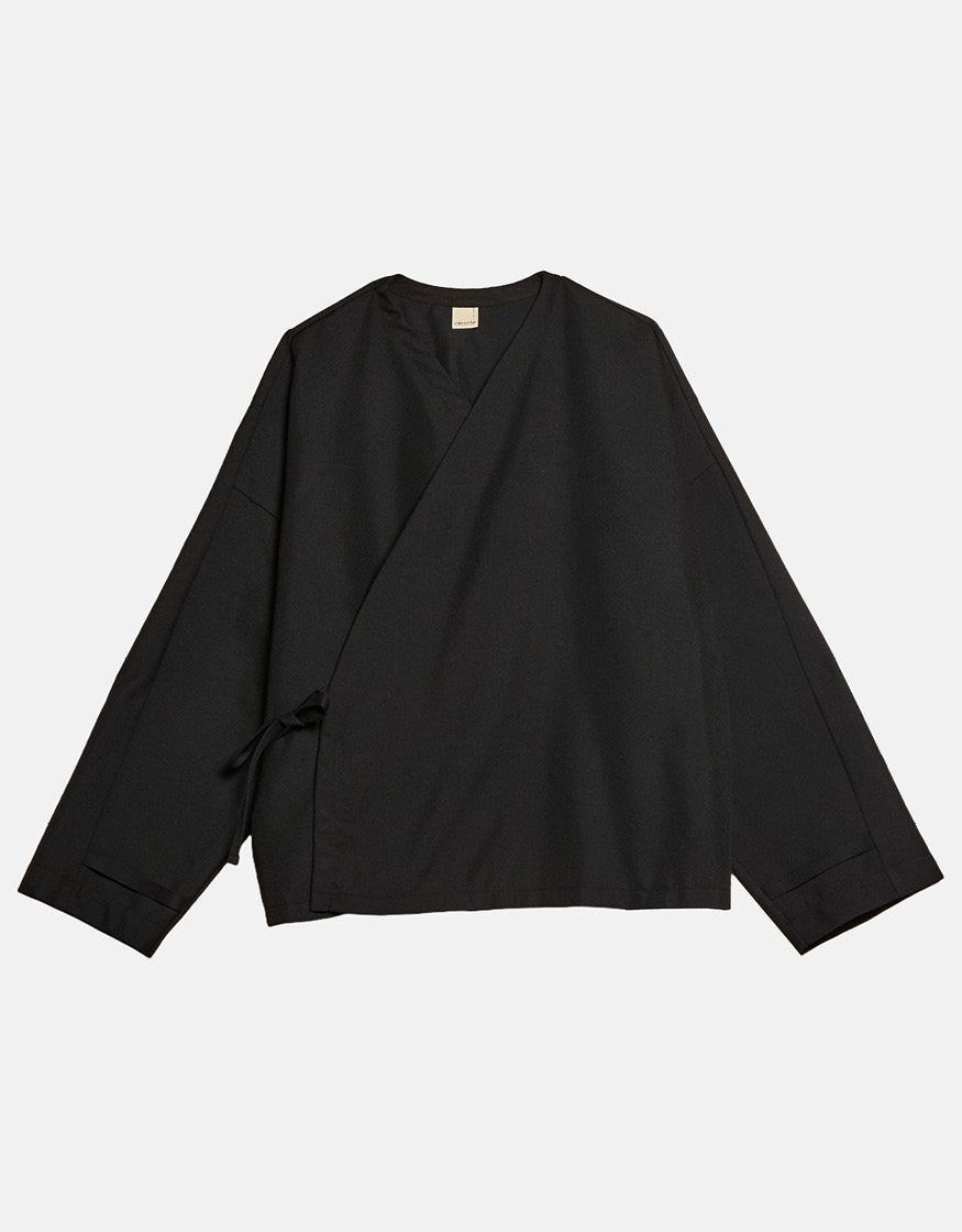 Minimalist black wrap-style top with asymmetrical design and subtle ties, crafted for comfort and understated elegance reflecting contemporary unisex fashion.