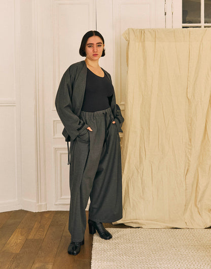 Unisex kimono, straight cut, oversized, low armholes, quilted strap at bottom of sleeves to modify volume, asymmetrical lines, cross-over front, closes with cotton taffeta ties of different widths. Designed to be worn both closed and open as an overshirt.
Made in France, in a Storm Grey light, fluid and crease resistant suiting, 65% Polyester, 35% Wool, 198g/m², from a fashion house's dead stock.