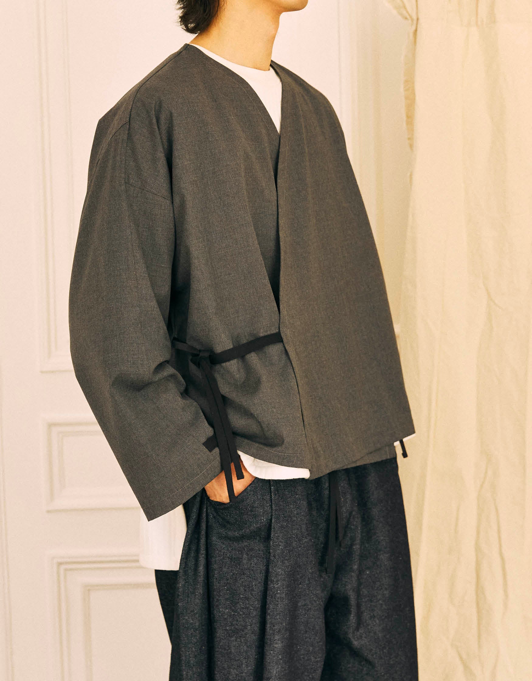 Unisex kimono, straight cut, oversized, low armholes, quilted strap at bottom of sleeves to modify volume, asymmetrical lines, cross-over front, closes with cotton taffeta ties of different widths. Designed to be worn both closed and open as an overshirt.
Made in France, in a Storm Grey light, fluid and crease resistant suiting, 65% Polyester, 35% Wool, 198g/m², from a fashion house's dead stock.