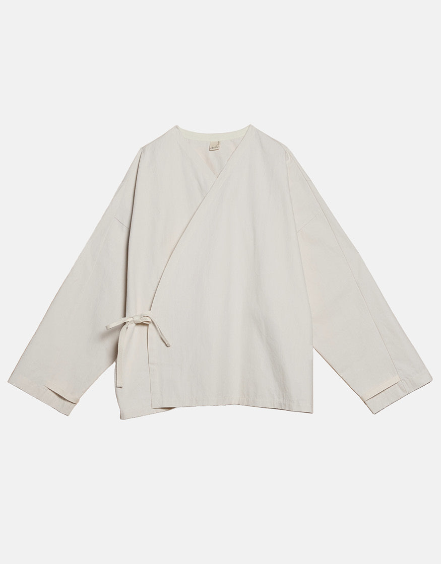 Off-white minimalist unisex kimono-style top with asymmetrical wrap design and subtle tie closure, emphasizing clean lines and timeless, understated elegance.