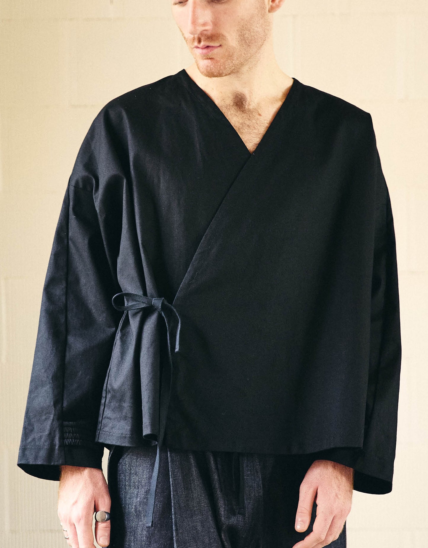 Unisex kimono, straight cut, oversized, low armholes, quilted strap at the bottom of the sleeves to modify volume, asymmetrical lines, cross-over front, closes with cotton taffeta ties of different widths. Designed to be worn both closed and open as an overshirt.
Made in France, in a Black stretch cotton gabardine, 98% Cotton, 2% Elastane, 251g/m², from a fashion house's dead stock.