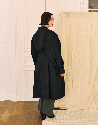 Unisex light coat, straight cut, oversized, low armholes, quilted strap at bottom of sleeves to modify volume, two wide pockets, asymmetrical lines, two wide pleats in back, cross-over front, closed by a belt.
Made in France, in a Black stretch cotton gabardine, 98% Cotton, 2% Elastane, 251g/m², from a fashion house's dead stock.