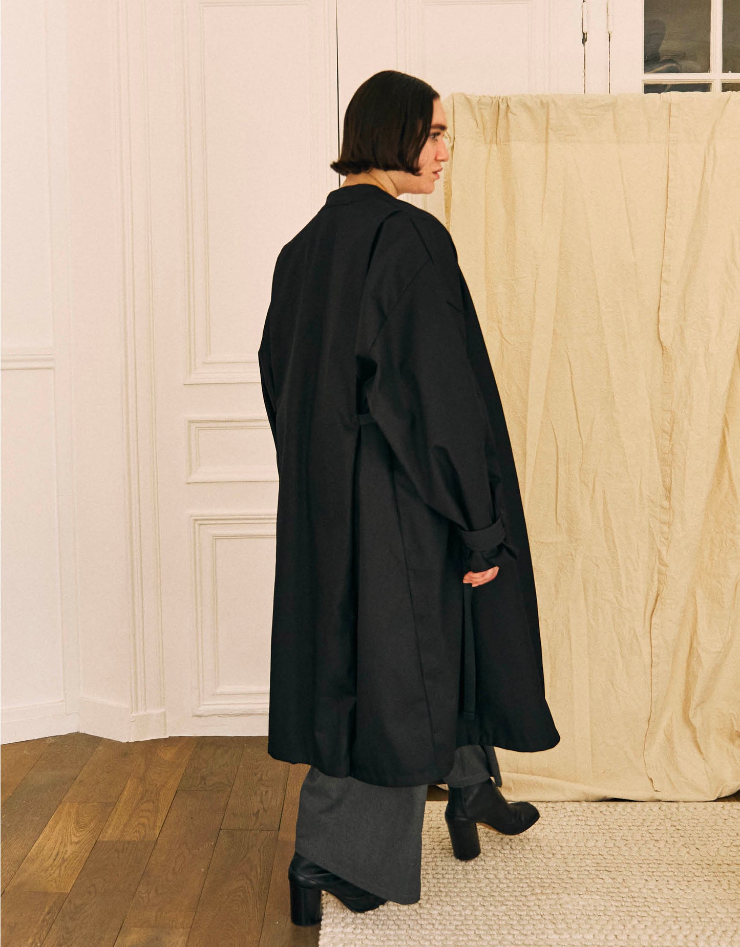 Unisex light coat, straight cut, oversized, low armholes, quilted strap at bottom of sleeves to modify volume, two wide pockets, asymmetrical lines, two wide pleats in back, cross-over front, closed by a belt.
Made in France, in a Black stretch cotton gabardine, 98% Cotton, 2% Elastane, 251g/m², from a fashion house's dead stock.