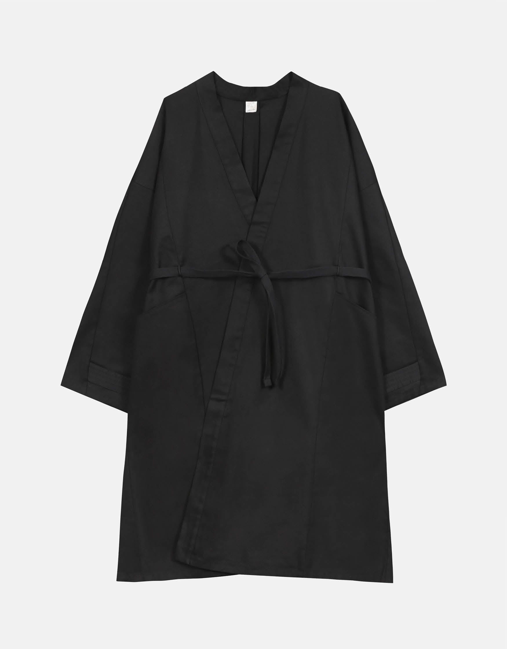 Unisex light coat, straight cut, oversized, low armholes, quilted strap at bottom of sleeves to modify volume, two wide pockets, asymmetrical lines, two wide pleats in back, cross-over front, closed by a belt.
Made in France, in a Black stretch cotton gabardine, 98% Cotton, 2% Elastane, 251g/m², from a fashion house's dead stock.