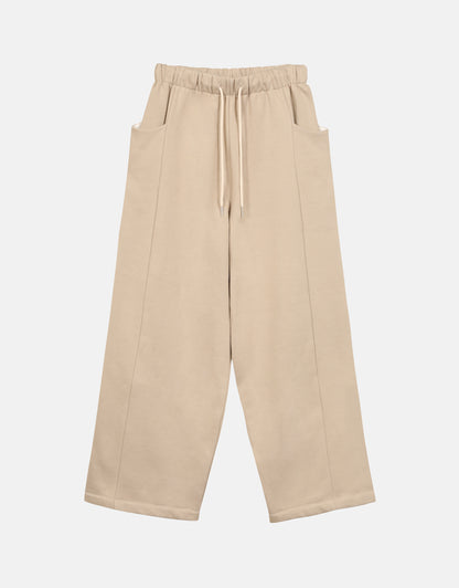 Pantalon - Chapitre 1, unisexe, jambes amples et droites, deux poches latérales, ceinture élastiquée, ajustable avec un cordon, dans un molleton gratté beige. Pants - Chapter 1, unisex, wide, straight legs, two side pockets, elasticated belt, adjustable with drawstring, in a beige brushed cotton fleece. Chaque pièce est numérotée.