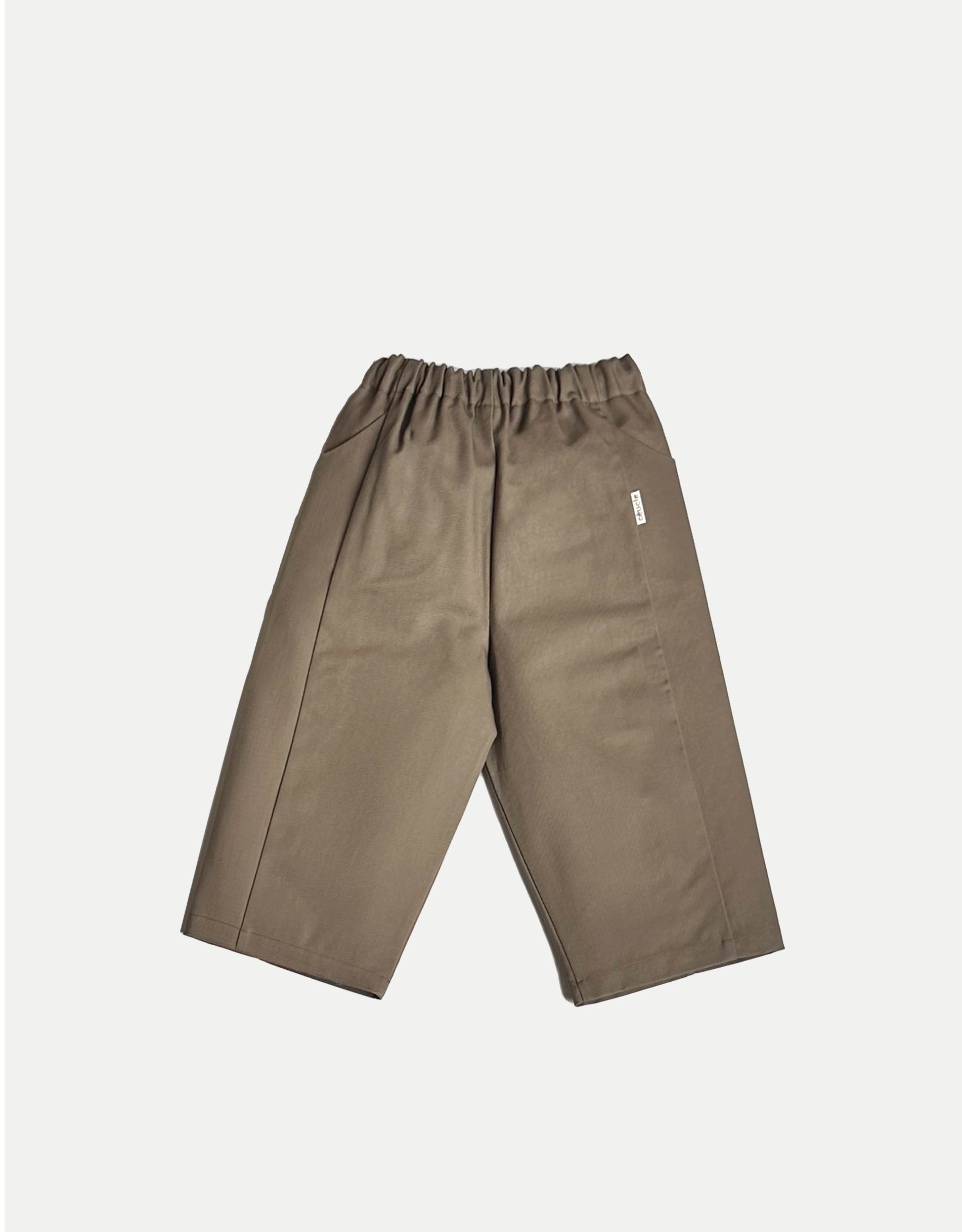 Pantalon pour enfant, taupe, jambes larges et droites. Taille élastiquée, ceinture réglable avec cordon. Deux poches. Upcyclé, minimal et oversized. Made in France. Kid pants, taupe, wide, straight legs. Elasticated waistband, adjustable waistband with drawstring. Two pockets. Upcycled, minimal and oversized. Made in France.