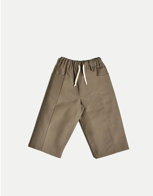Pantalon pour enfant, taupe, jambes larges et droites. Taille élastiquée, ceinture réglable avec cordon. Deux poches. Upcyclé, minimal et oversized. Made in France. Kid pants, taupe, wide, straight legs. Elasticated waistband, adjustable waistband with drawstring. Two pockets. Upcycled, minimal and oversized. Made in France.
