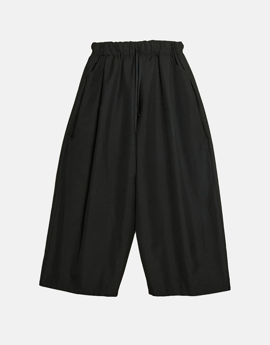 Black wide pants with a minimalist design featuring an elastic waistband and loose, flowing silhouette emphasizing comfort and freedom of movement.