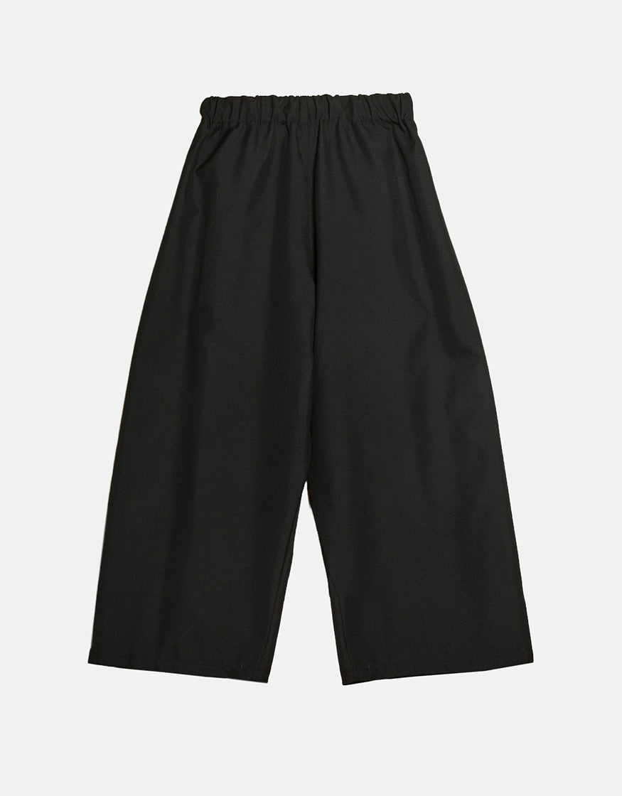 Wide black pants with a minimalist design featuring an elastic waistband, crafted for comfort and freedom of movement with a contemporary unisex style.