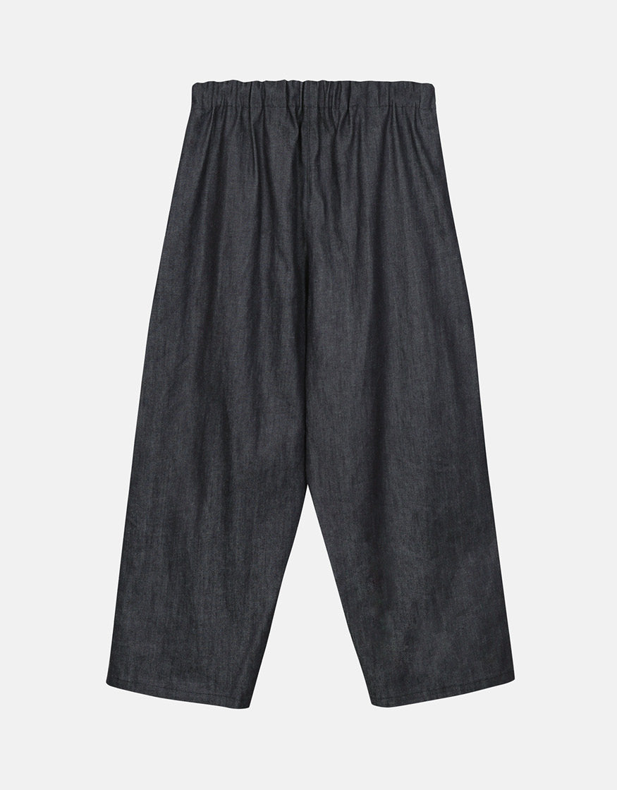 Minimalist wide-leg indigo pants with elastic waistband, featuring a relaxed silhouette designed for comfort and effortless movement in a timeless style.