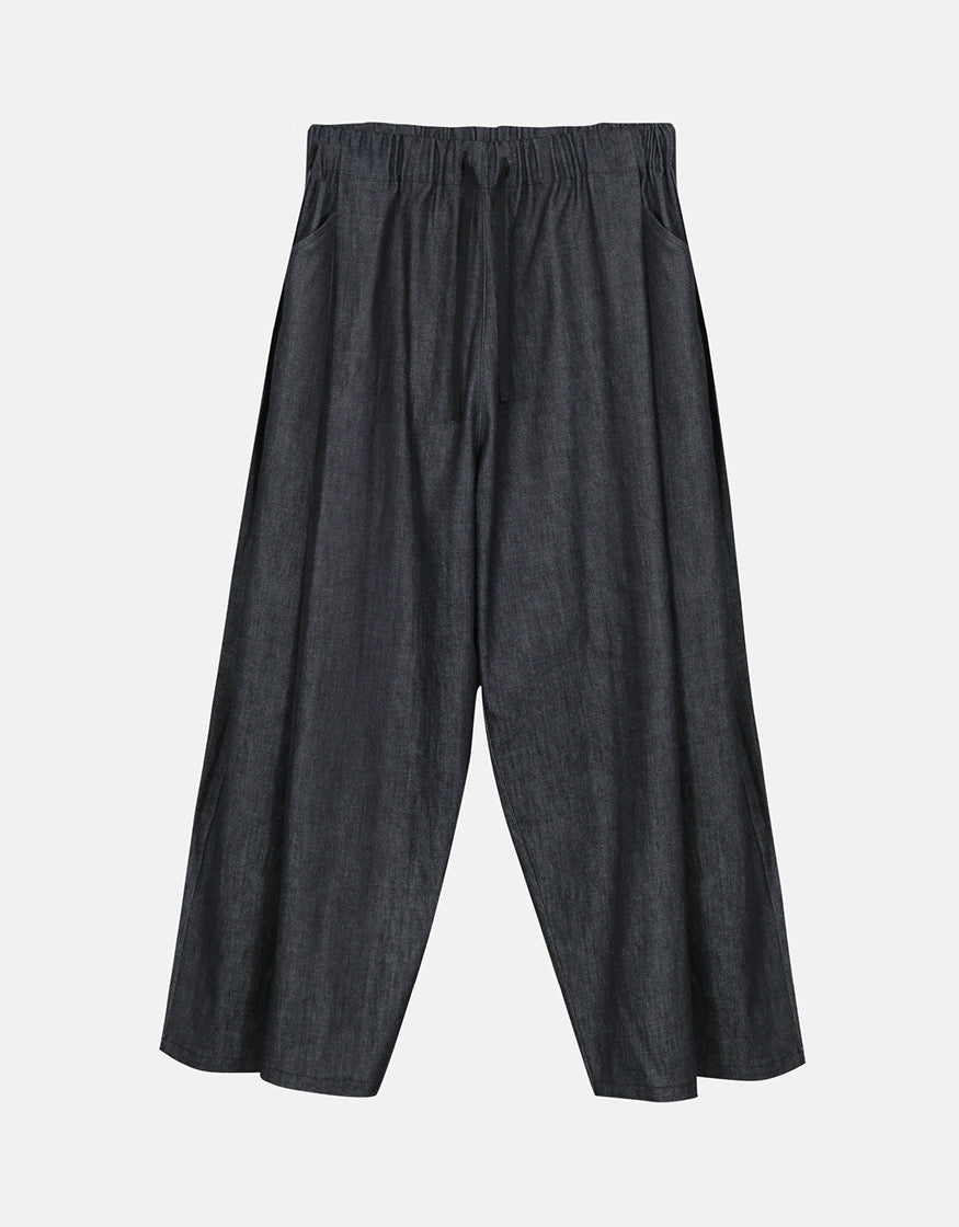 Unisex wide-leg indigo pants with an elastic waistband and subtle volume, designed for comfort and understated elegance with a minimalist aesthetic.