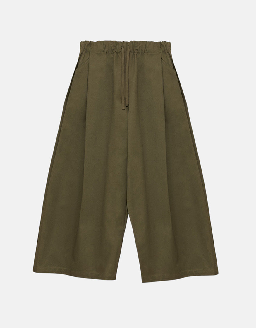 Unisex wide sage green pants with a relaxed silhouette, elastic waistband, and drawstring, embodying minimalist design and freedom of movement with subtle volume.