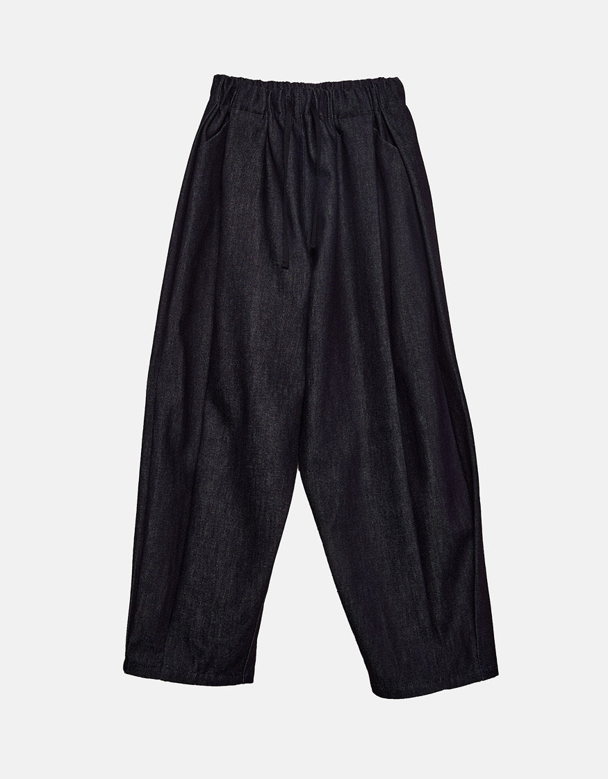 Loose-fitting indigo pants with a minimalist design, featuring an elastic waistband for comfort and a focus on understated elegance and freedom of movement.