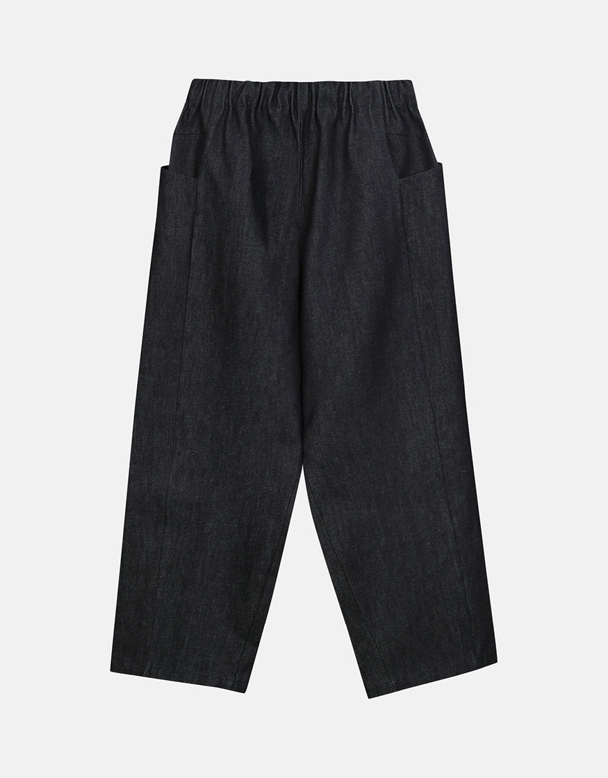 Minimalist tapered indigo pants featuring an elastic waistband and side pockets, designed for understated elegance and comfortable movement.