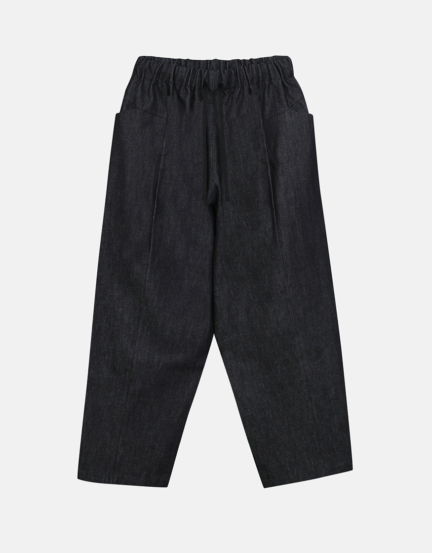 Unisex tapered pants in deep indigo with an elastic waistband, designed for comfort and subtle volume to allow freedom of movement in a minimalist silhouette.