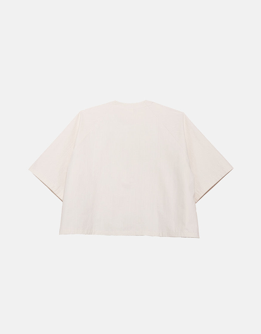Off-white minimalist short sleeve shirt with a boxy silhouette, designed for unisex wear, emphasizing clean lines and subtle volume for ease of movement.
