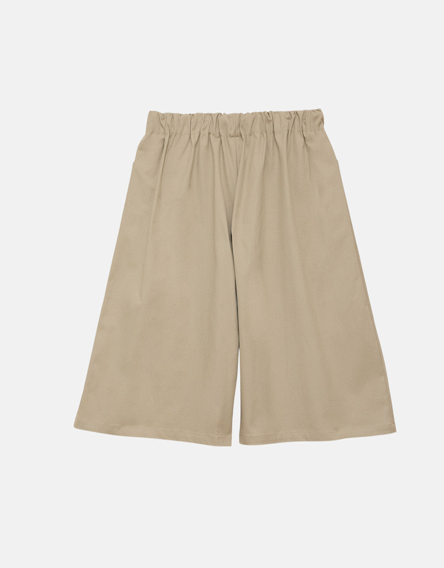 Beige wide-leg shorts with a straight cut and elastic waistband, designed for a minimalist, unisex look emphasizing comfort and understated elegance.