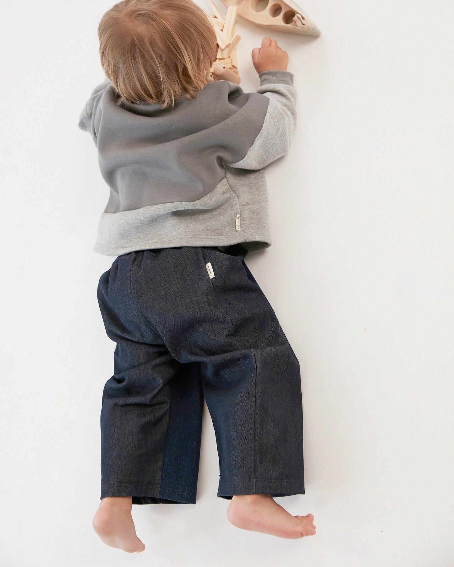 Pantalon pour enfant, jean, jambes larges et droites. Taille élastiquée, ceinture réglable avec cordon. Deux poches. Upcyclé, minimal et oversized. Made in France. Kid pants, denim, wide, straight legs. Elasticated waistband, adjustable waistband with drawstring. Two pockets. Upcycled, minimal and oversized. Made in France.